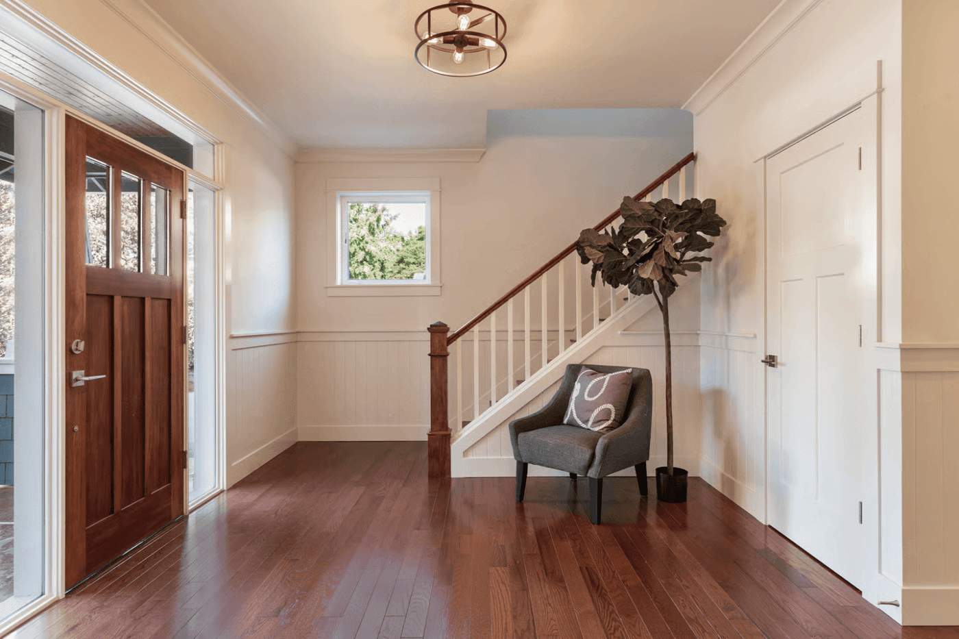 Freshly painted entryway with a wood front door and staircase